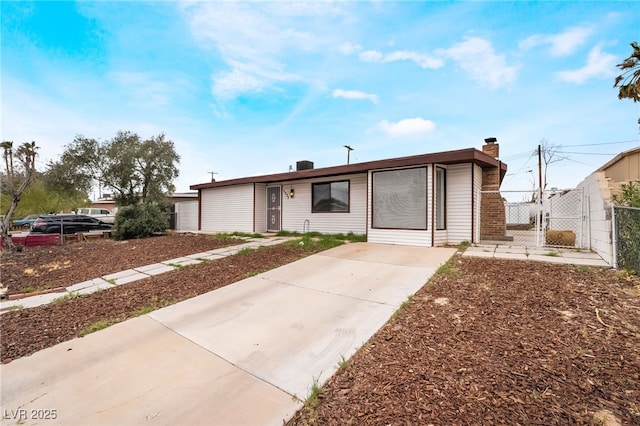 single story home featuring a chimney, fence, and a gate