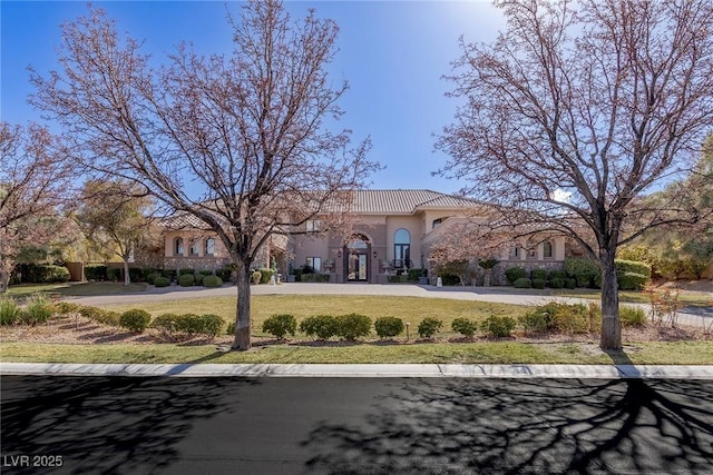 view of front of house with a front yard, a tile roof, driveway, and stucco siding