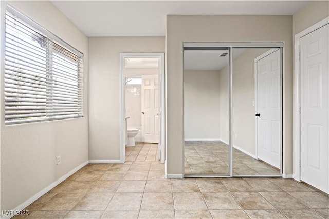 unfurnished bedroom featuring light tile patterned floors, a closet, visible vents, and baseboards