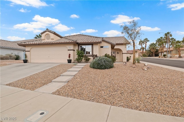 view of front of property featuring concrete driveway, a tiled roof, an attached garage, and stucco siding