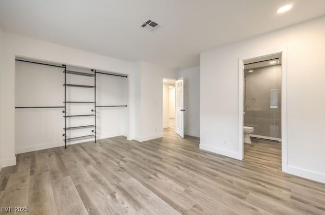 unfurnished bedroom with light wood-type flooring, visible vents, connected bathroom, and baseboards