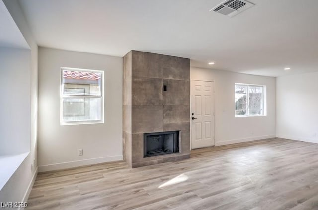 unfurnished living room featuring recessed lighting, wood finished floors, visible vents, baseboards, and a tiled fireplace