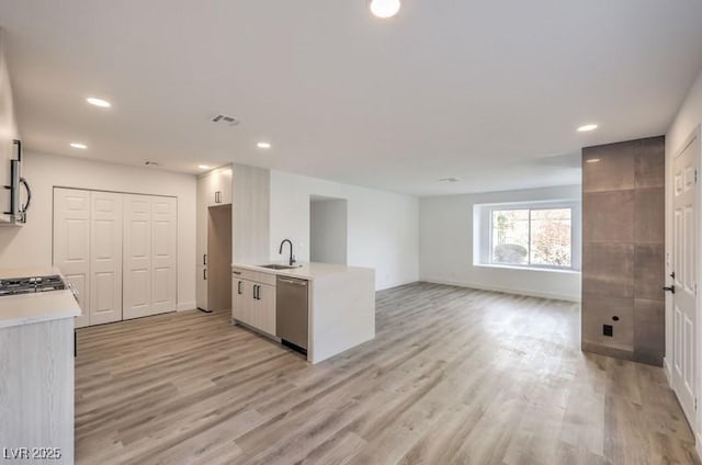 kitchen with a sink, visible vents, light countertops, stainless steel dishwasher, and light wood finished floors