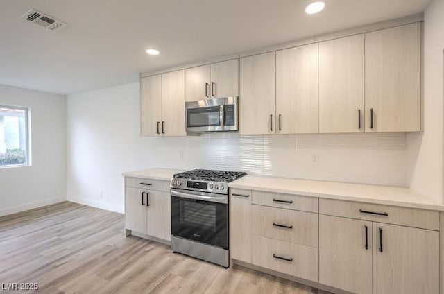 kitchen featuring stainless steel appliances, visible vents, decorative backsplash, and light brown cabinetry