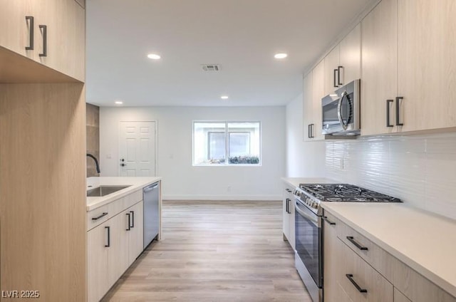 kitchen featuring tasteful backsplash, light countertops, visible vents, appliances with stainless steel finishes, and a sink