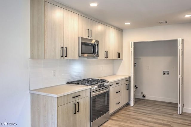 kitchen with tasteful backsplash, visible vents, stainless steel appliances, light wood-style floors, and light brown cabinets