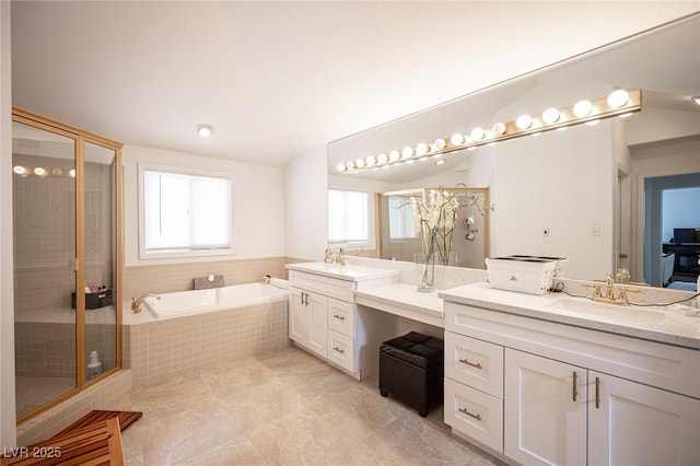 bathroom with a stall shower, a sink, a garden tub, vaulted ceiling, and two vanities