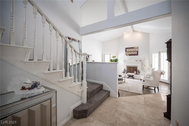 stairs with high vaulted ceiling, a fireplace, and beamed ceiling