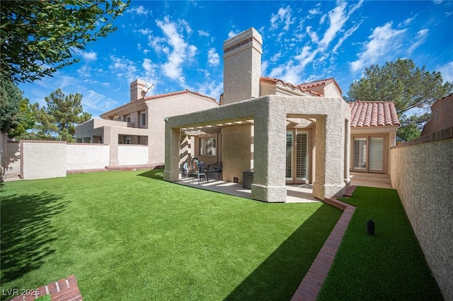 rear view of property featuring a fenced backyard, a tile roof, a yard, stucco siding, and a patio area