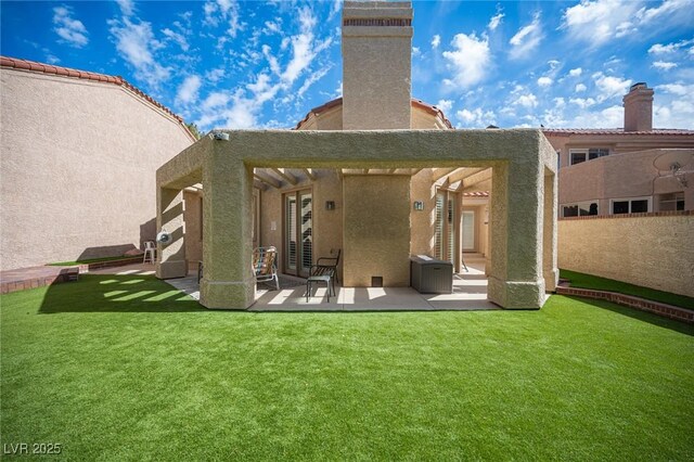 rear view of property featuring a lawn, a patio, and stucco siding