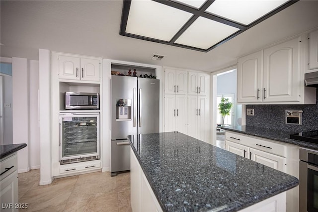 kitchen with beverage cooler, visible vents, white cabinetry, appliances with stainless steel finishes, and tasteful backsplash