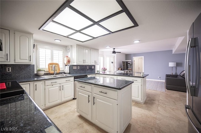 kitchen featuring a peninsula, stainless steel appliances, a sink, white cabinetry, and backsplash