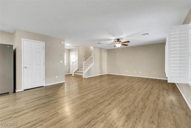 unfurnished living room featuring visible vents, a ceiling fan, light wood-type flooring, baseboards, and stairs