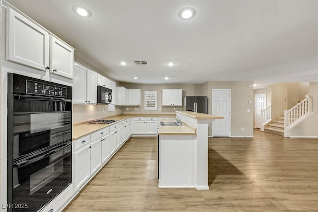 kitchen featuring black appliances, a sink, visible vents, and light wood-style floors