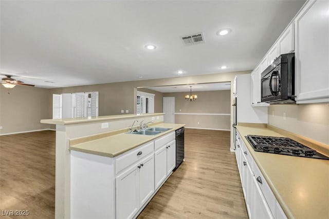 kitchen with visible vents, open floor plan, light wood-type flooring, black appliances, and a sink