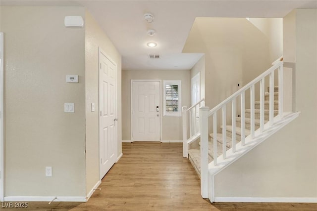 foyer entrance with stairway, wood finished floors, visible vents, and baseboards