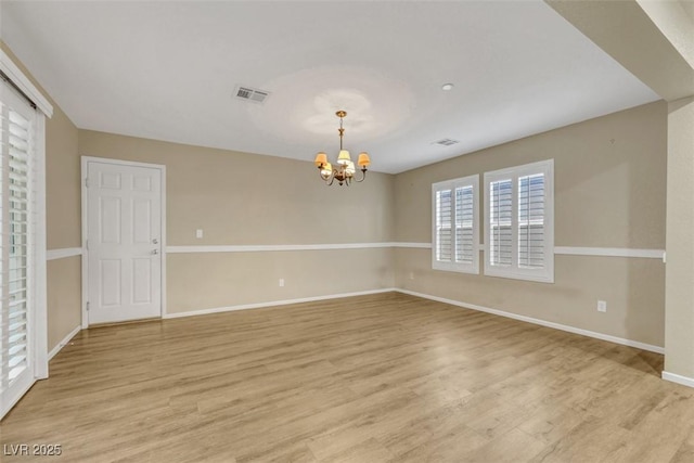 unfurnished room featuring a chandelier, visible vents, and light wood-style floors