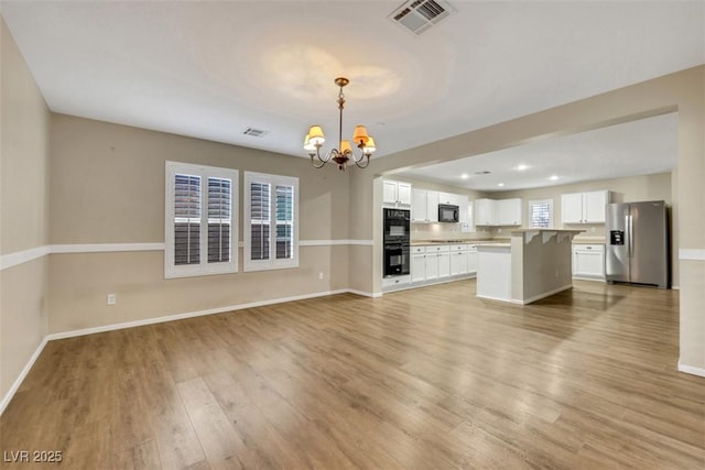 unfurnished living room featuring light wood-style floors, visible vents, and a notable chandelier