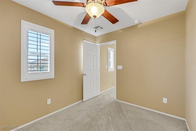 spare room featuring carpet floors, visible vents, baseboards, and a ceiling fan