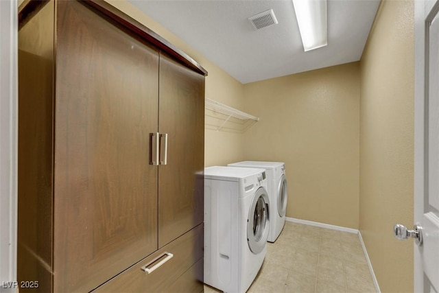 clothes washing area with washer and dryer, laundry area, visible vents, and baseboards