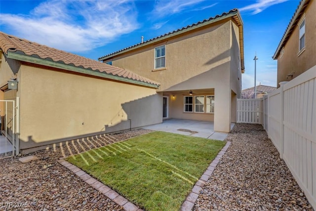 back of house with a fenced backyard, a ceiling fan, a tiled roof, stucco siding, and a patio area