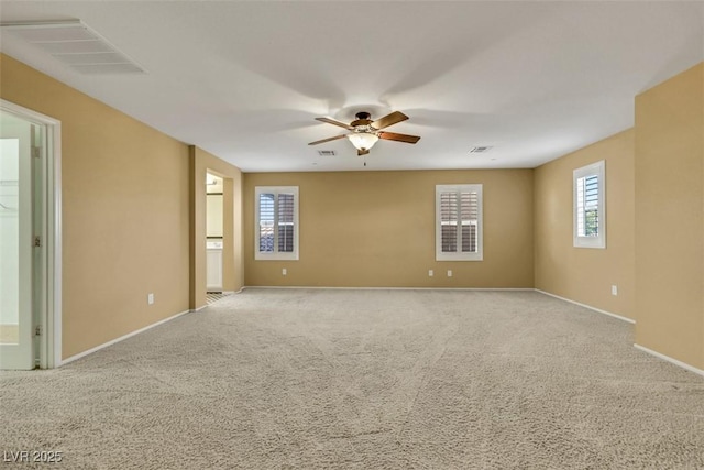 carpeted empty room featuring baseboards, visible vents, and a ceiling fan