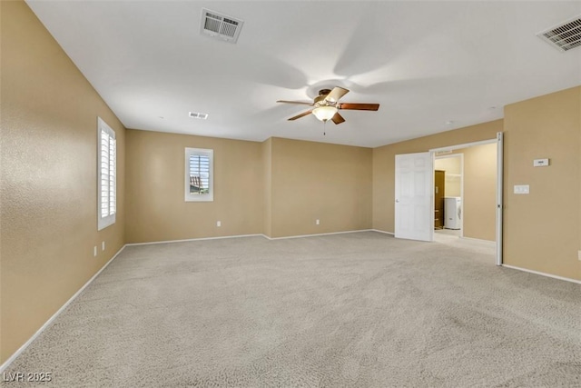 empty room featuring a ceiling fan, light colored carpet, visible vents, and baseboards