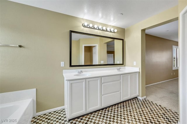 bathroom with a sink, a bathing tub, and baseboards