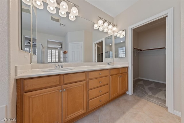 bathroom with double vanity, tile patterned flooring, a walk in closet, and a sink