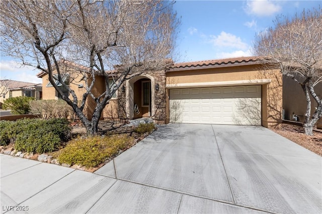 mediterranean / spanish home featuring a garage, a tile roof, concrete driveway, stone siding, and stucco siding