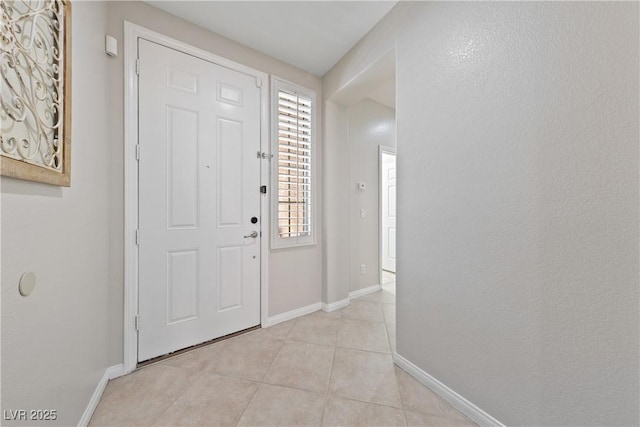 foyer entrance featuring light tile patterned flooring and baseboards