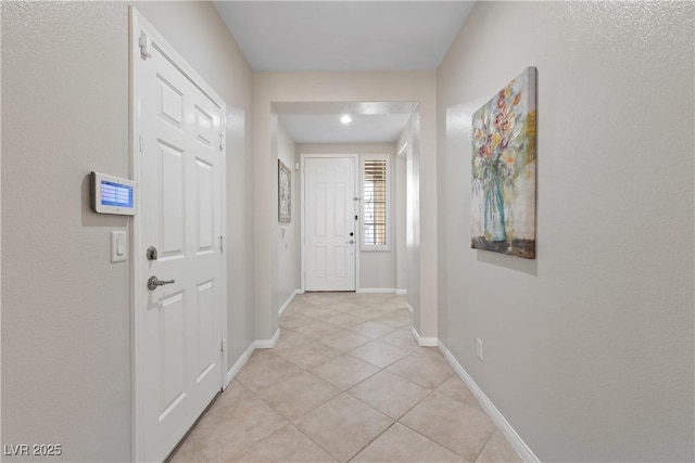 doorway featuring light tile patterned floors and baseboards