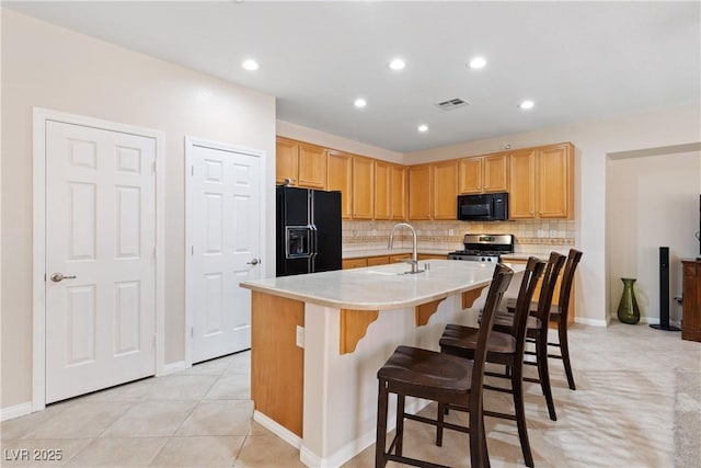 kitchen with a sink, visible vents, light countertops, backsplash, and black appliances