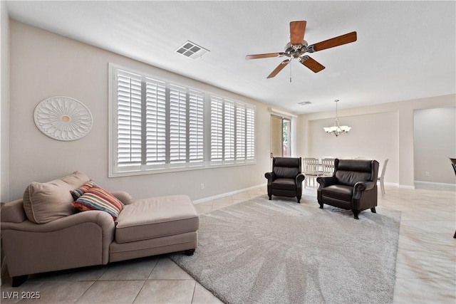 living area with tile patterned flooring, visible vents, baseboards, and ceiling fan with notable chandelier