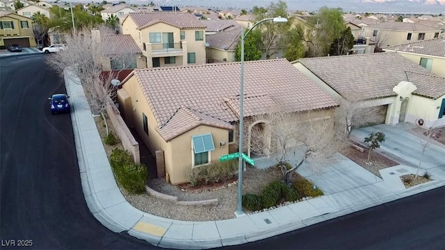 view of front of property featuring concrete driveway, a residential view, a tiled roof, an attached garage, and stucco siding