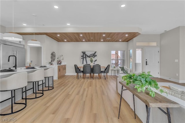 kitchen featuring light wood finished floors, a breakfast bar, recessed lighting, light countertops, and built in refrigerator