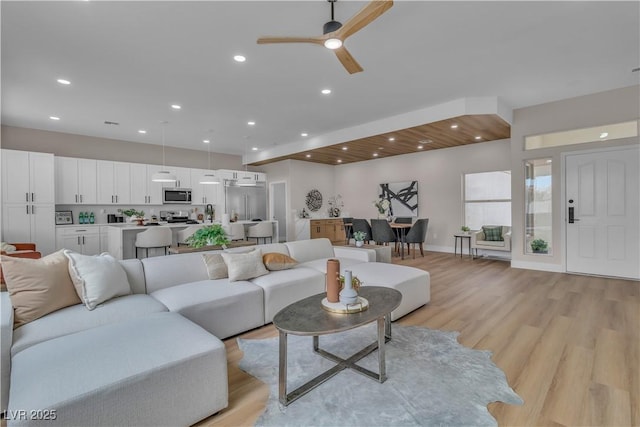 living room with light wood finished floors, ceiling fan, baseboards, and recessed lighting