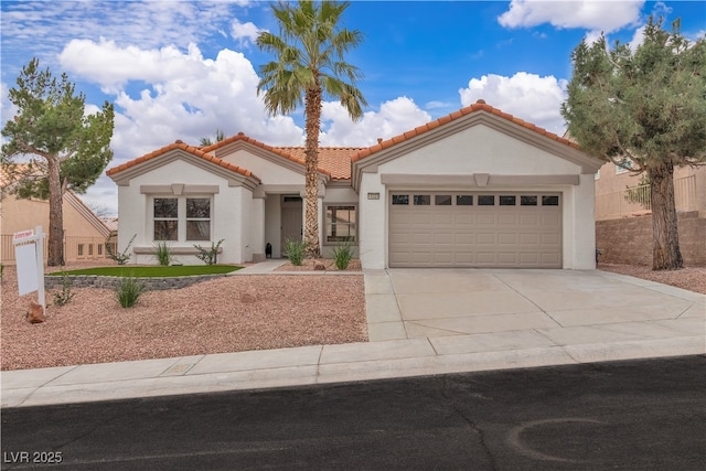 mediterranean / spanish-style home with a garage, a tiled roof, concrete driveway, and stucco siding