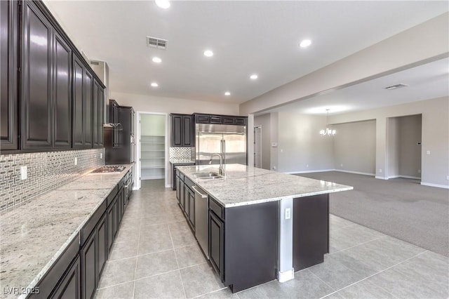 kitchen featuring light tile patterned floors, visible vents, appliances with stainless steel finishes, a sink, and light stone countertops