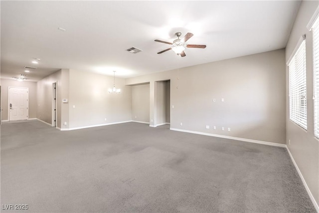 carpeted spare room featuring visible vents, baseboards, and ceiling fan with notable chandelier