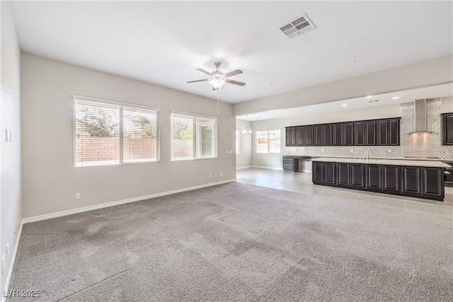 unfurnished living room with light carpet, a ceiling fan, visible vents, and baseboards