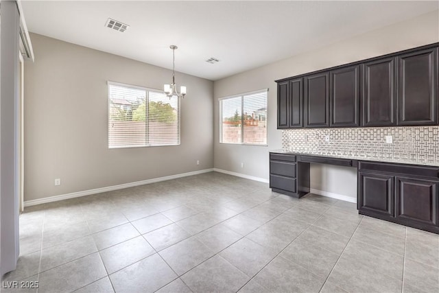 kitchen with a notable chandelier, light countertops, visible vents, backsplash, and light tile patterned flooring