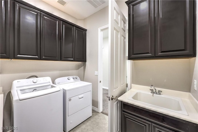 washroom with cabinet space, washing machine and dryer, visible vents, and a sink