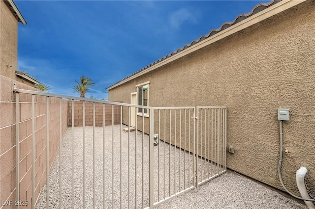 exterior space with a tile roof, a fenced backyard, a gate, and stucco siding