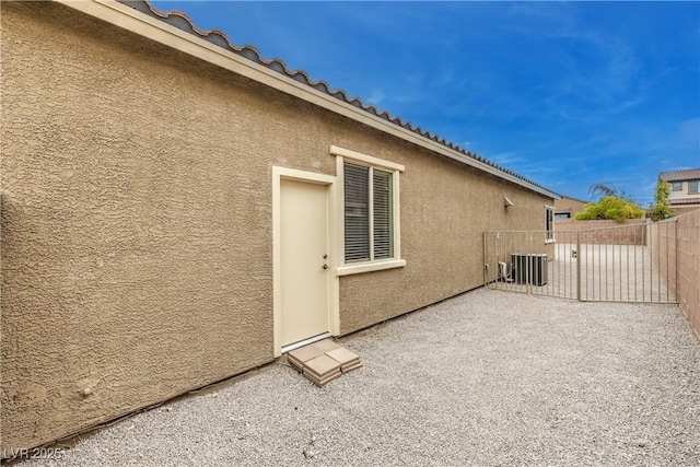 view of home's exterior with a patio, stucco siding, central AC unit, fence, and a tiled roof