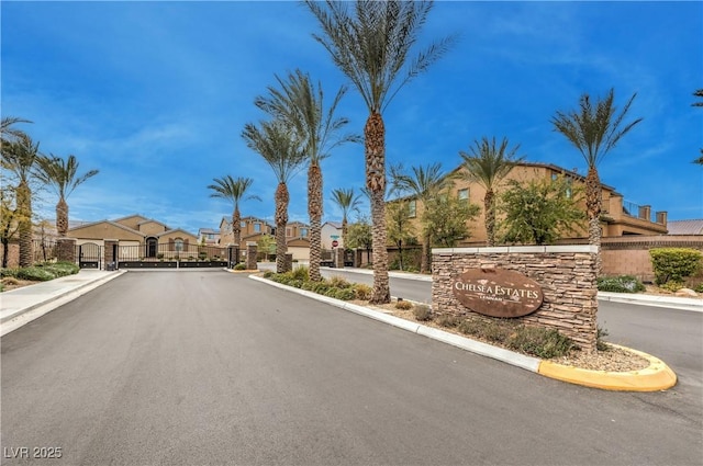 view of road with a gated entry, sidewalks, curbs, a gate, and a residential view