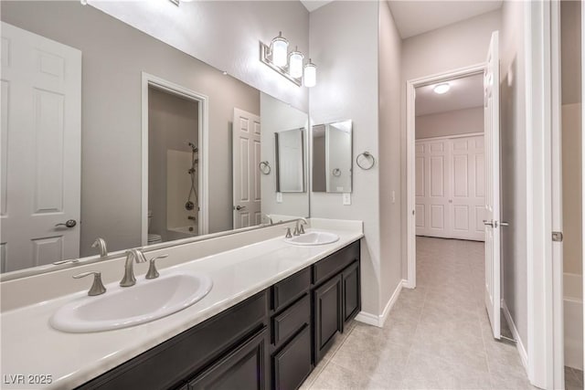 full bathroom featuring baseboards, a sink, toilet, and double vanity