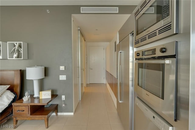 corridor with visible vents, baseboards, and light tile patterned floors