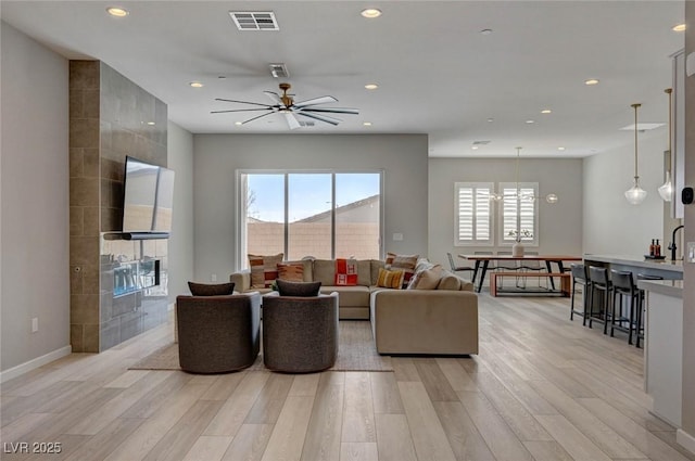 living area with light wood-type flooring, visible vents, baseboards, and recessed lighting