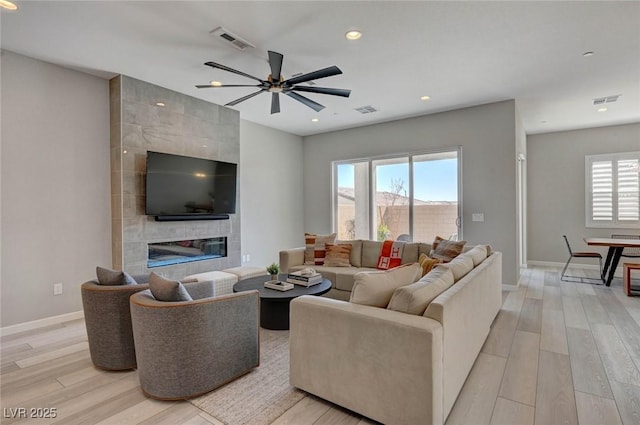 living area featuring recessed lighting, visible vents, a fireplace, and light wood-style flooring